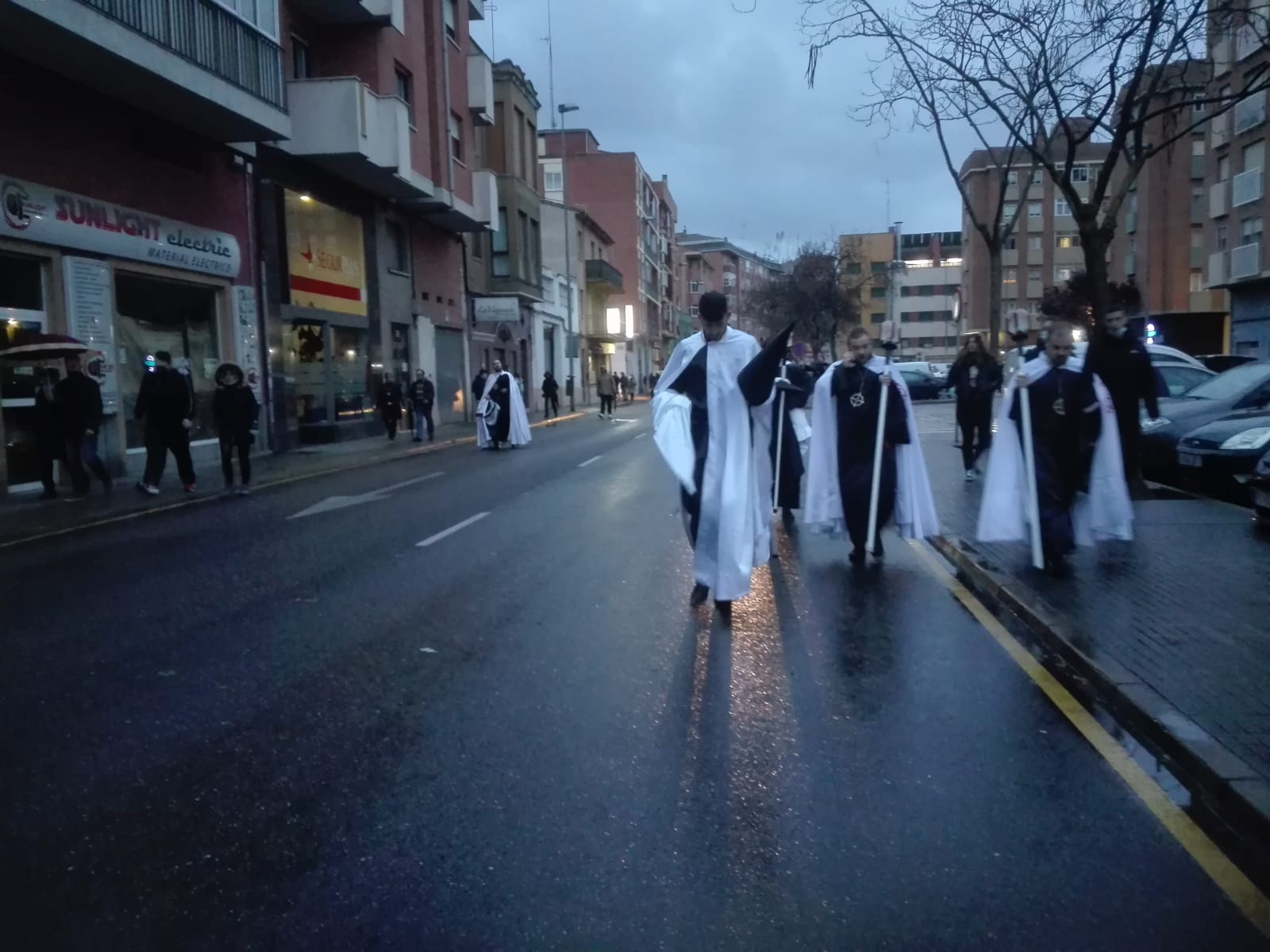 Varios cofrades de la Tercera Caída enfilan la calle Villalpando tras la suspensión del desfile