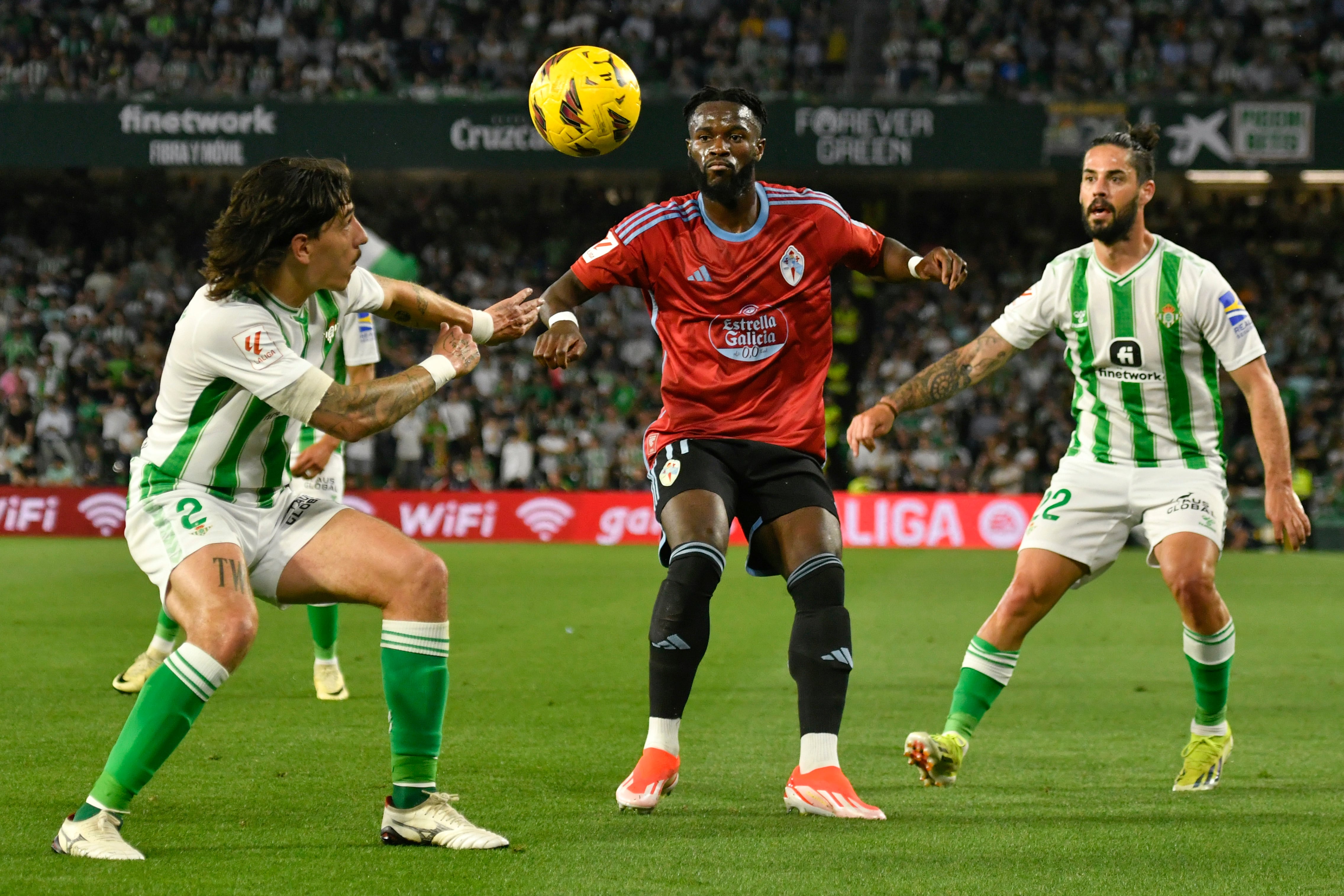 SEVILLA. 12/04/2024. - El delantero francés del Celta de Vigo, Jonathan Bamba (c), disputa el balón ante los jugadores del Betis, Héctor Bellerín (i) e Isco, durante el partido de liga perteneciente a la jornada 31 que se ha disputado esta tarde en el estadio Benito Villamarín de Sevilla. EFE/ Raúl Caro.
