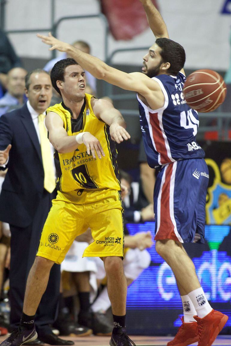  El base del Iberostar Tenerife, Daniel Pérez (i), realiza un pase ante el jugador del Rio Natura, Pepe Pozas, durante el encuentro correspondiente a la jornada de liga ACB, que han disputado esta noche en el pabellón Santiago Martín de La Laguna. 