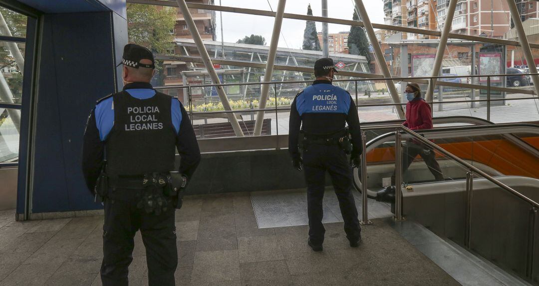 Dos Policías Locales de Leganés vigilan el acceso a una de las estaciones de Metrosur en la localidad.