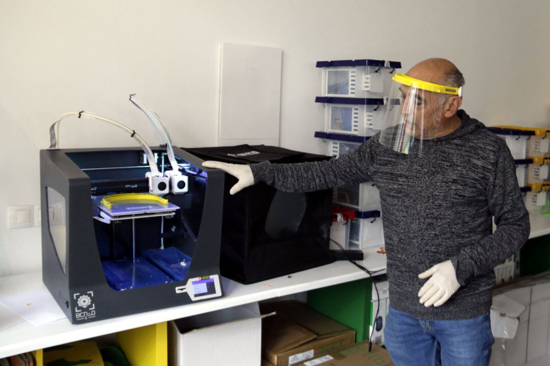 Pla mitjà del responsable d'Innova Didàctic d'Olot amb una de les impressores 3D que fan pantalles facials