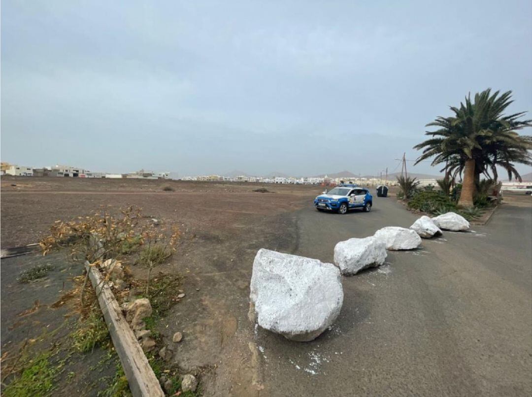 Coche patrulla de la Policía Local de Arrecife junto a las piedras que obstaculizan la calle.