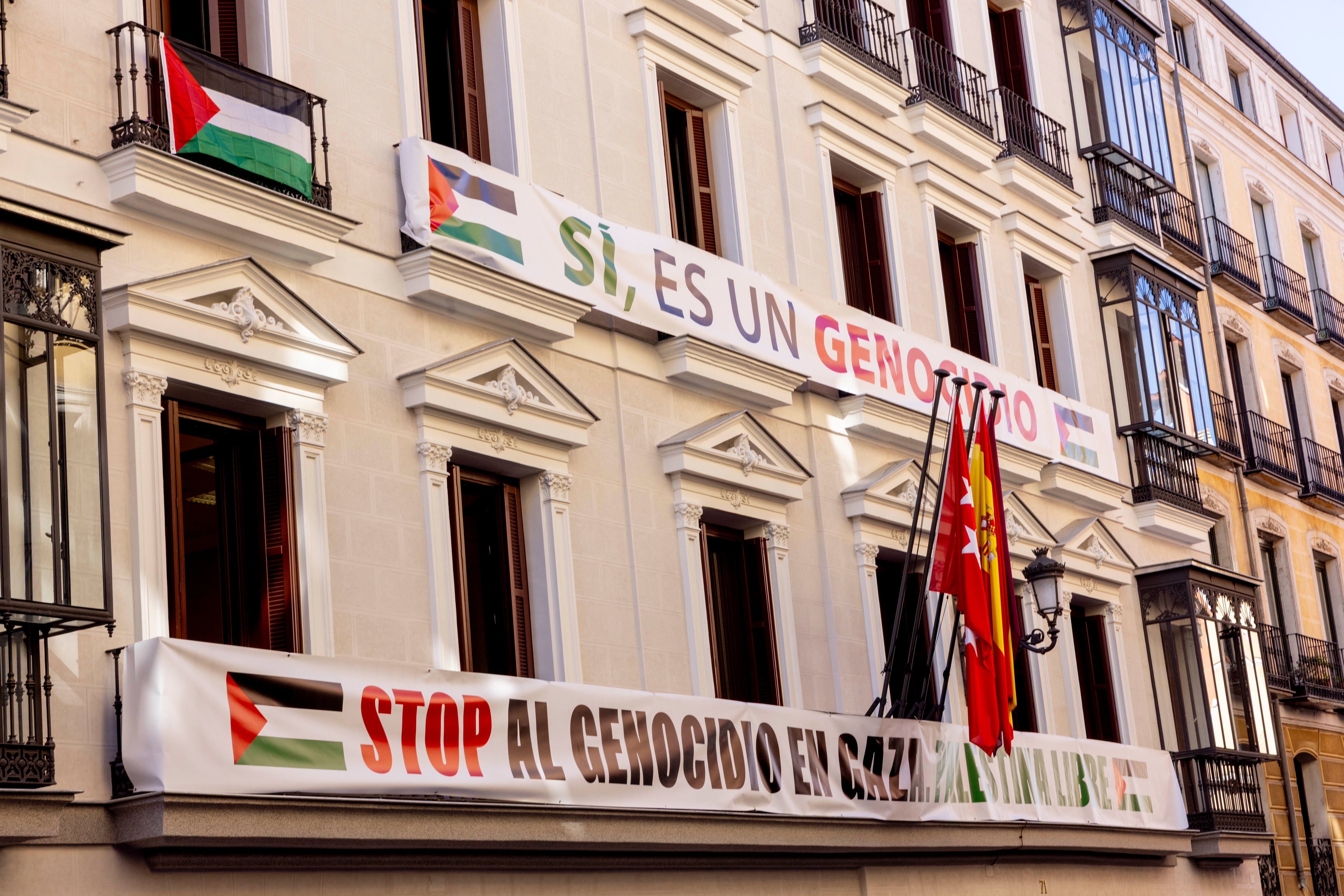 Pancartas desplegadas por Más Madrid contra el genocidio en Gaza, en la fachada del edificio de Grupos en la calle Mayor de Madrid