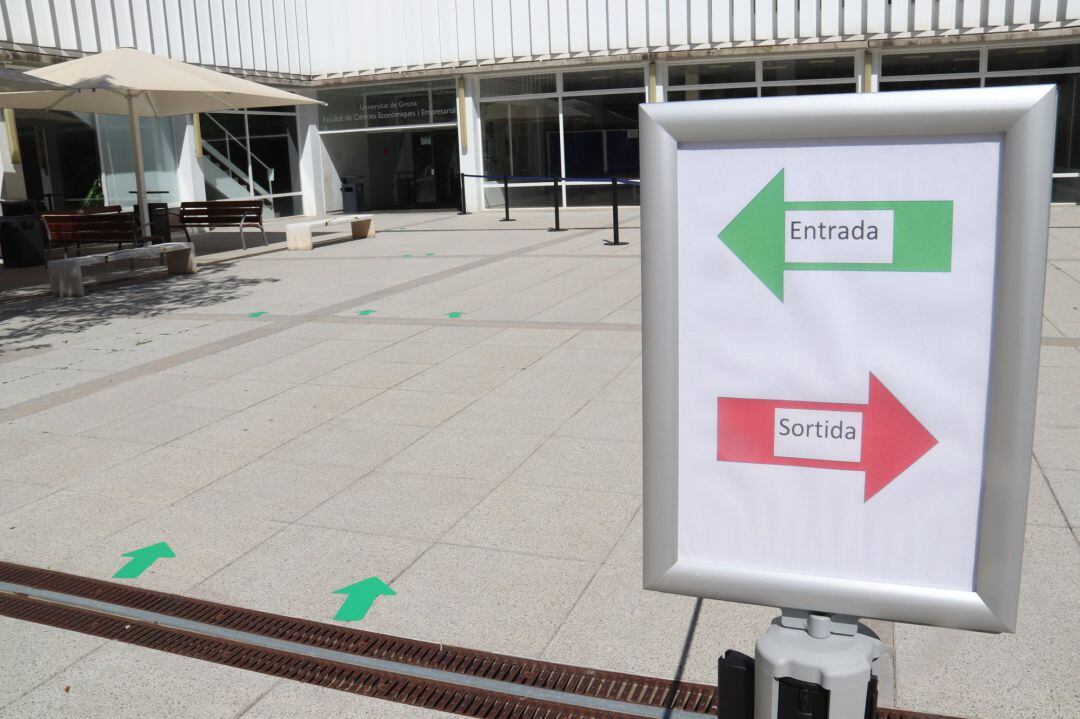 Les fletxes que indiquen el circuit d'entrada a la Facultat de Ciències Econòmiques que la UdG amb un cartell en primer terme que indica l'entrada i la sortida