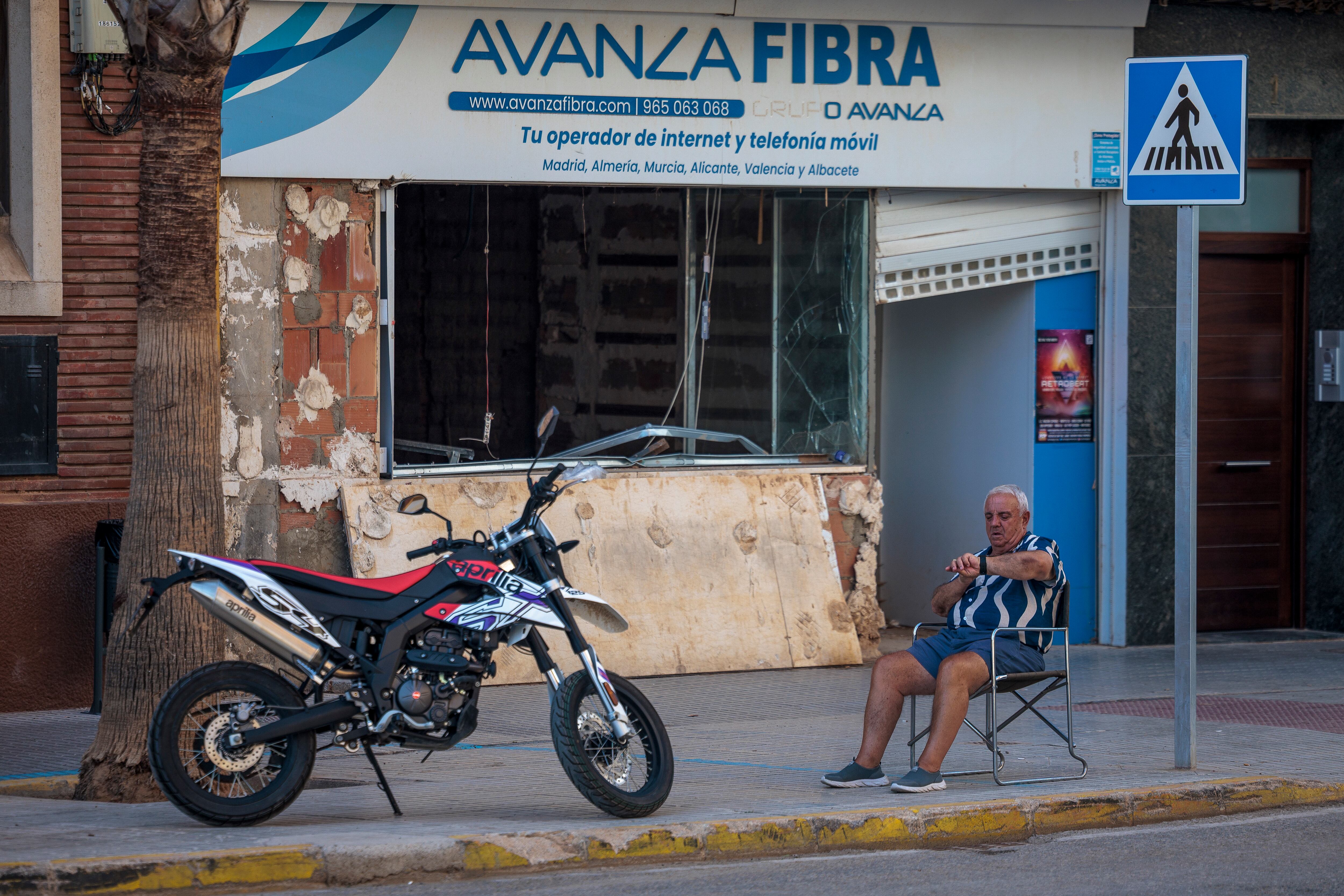 Una persona aguarda ante un comercio que muestra aún las consecuencias de la dana de Valencia en cuyas inundaciones murieron 228 personas y que cumple nueve meses mañana martes.