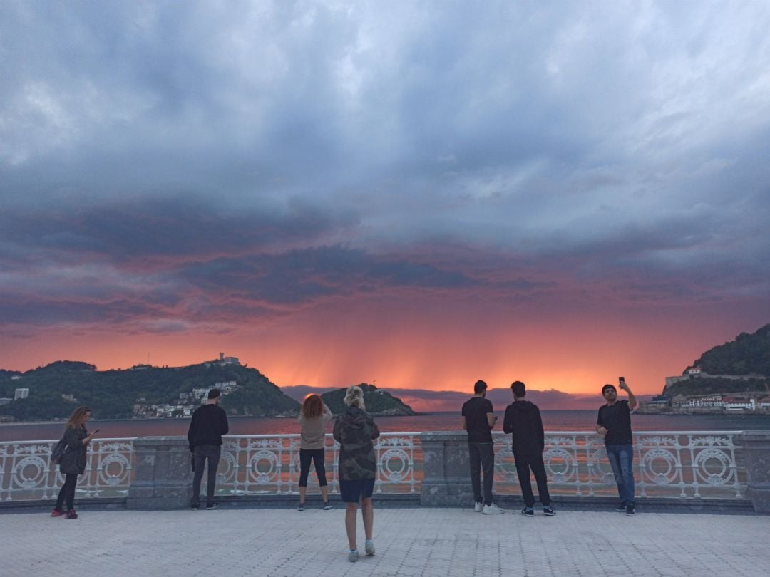 Unos turistas fotografían un atardecer en San Sebastián, en una imagen de archivo