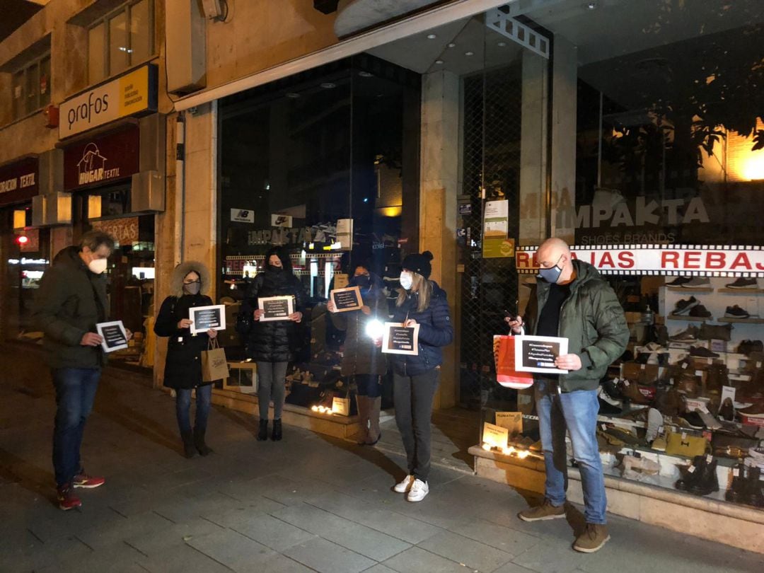 Los comerciantes se han concentrado ante sus negocios entre aplausos y velas.