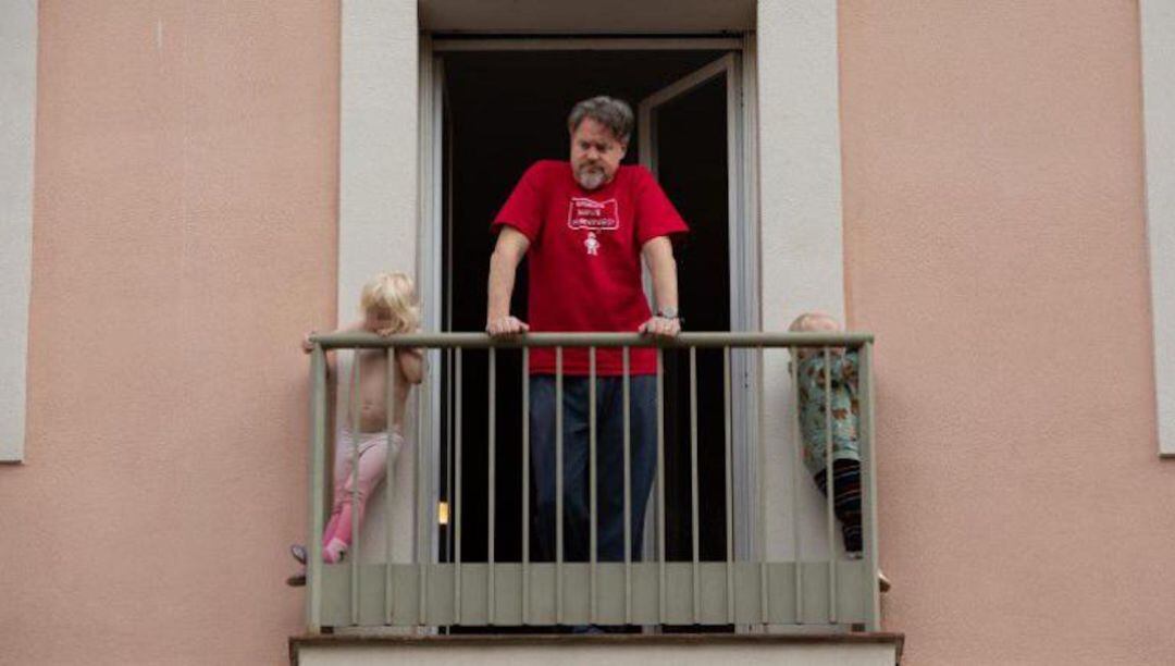 Un hombre y dos niños en el balcón de su vivienda durante el confinamiento
