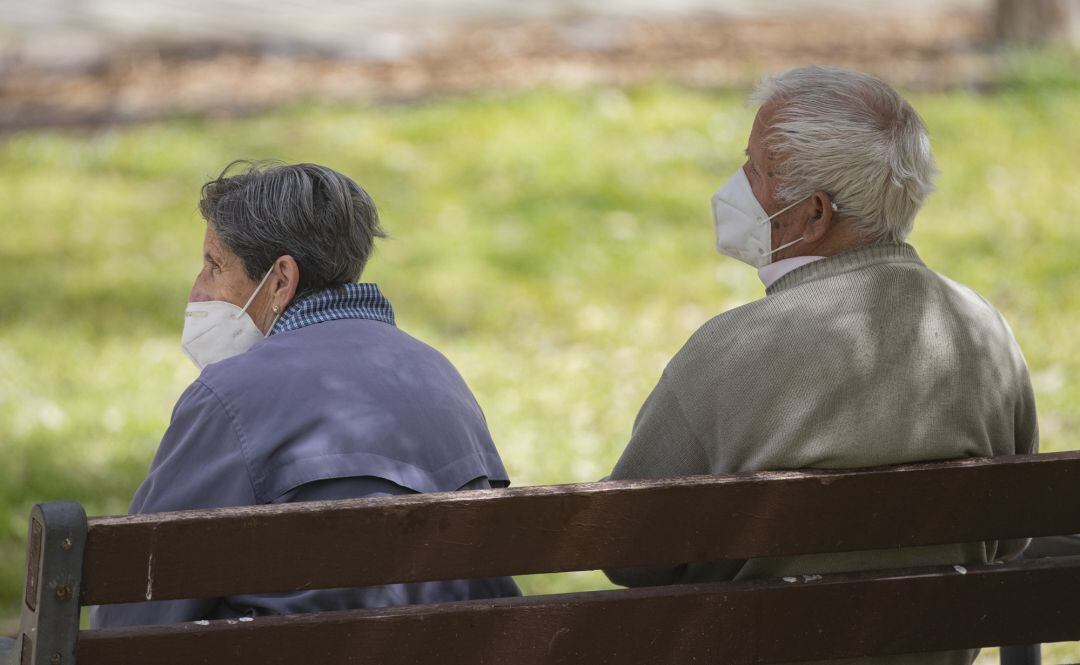 Dos personas con mascarilla descansan en el banco de un parque en una imagen de archivo. 