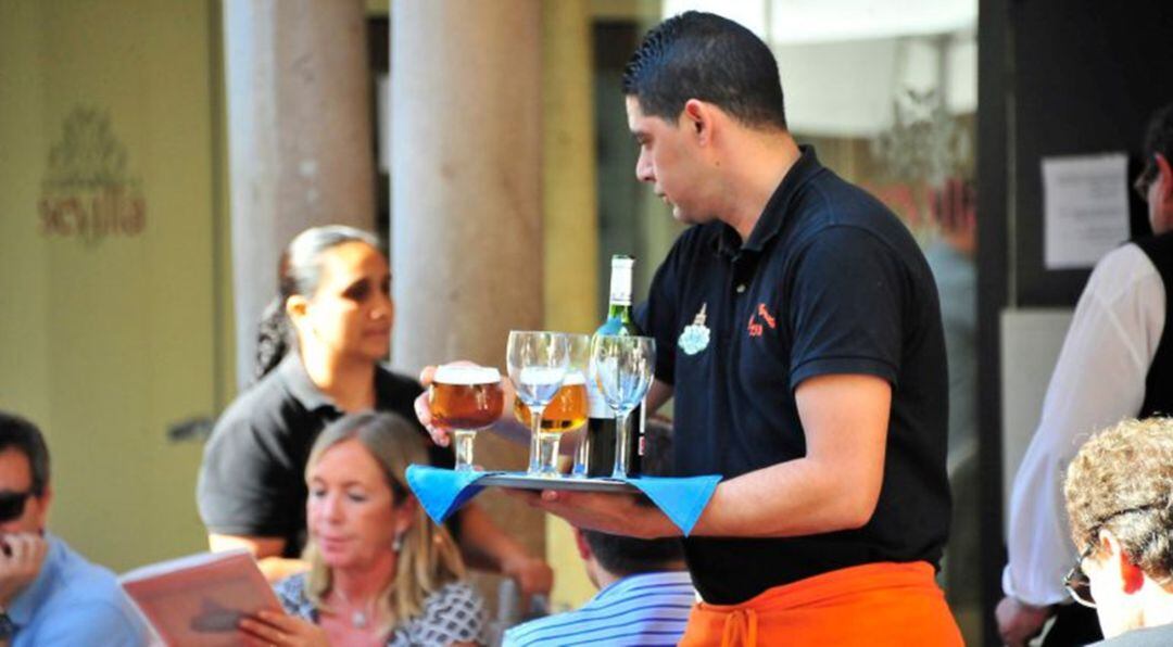 Un trabajador del sector de la hostelería atiende una mesa