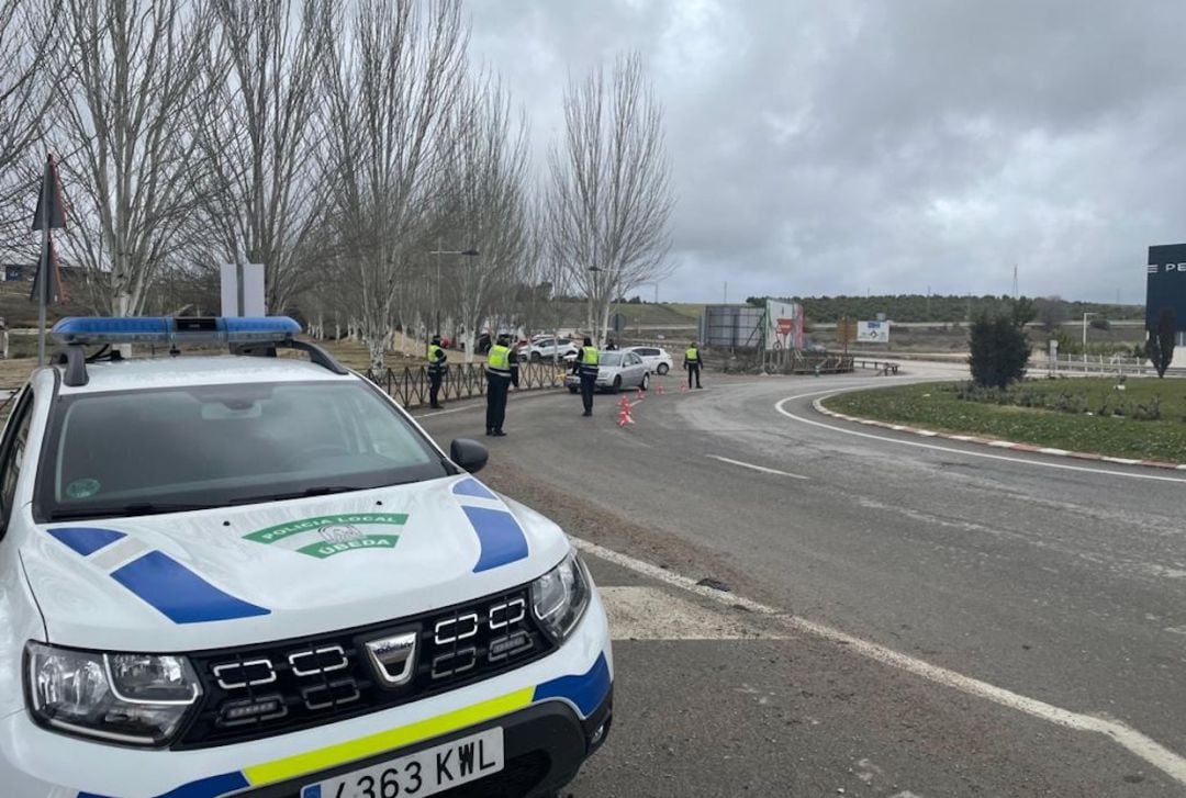 Vehículo de Policía Local estacionado en una glorieta en la que agentes realizan controles