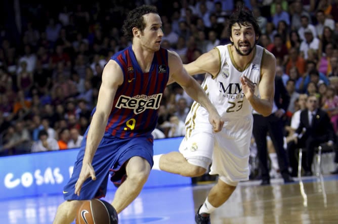 El base brasileño del F. C. Barcelona Regal, Marcelinho Huertas, conduce el balón ante el jugador del Real Madrid, Sergio Llull, durante el encuentro correspondiente al segundo partido de la final de la liga ACB, que disputan este viernes en el Palau Balu