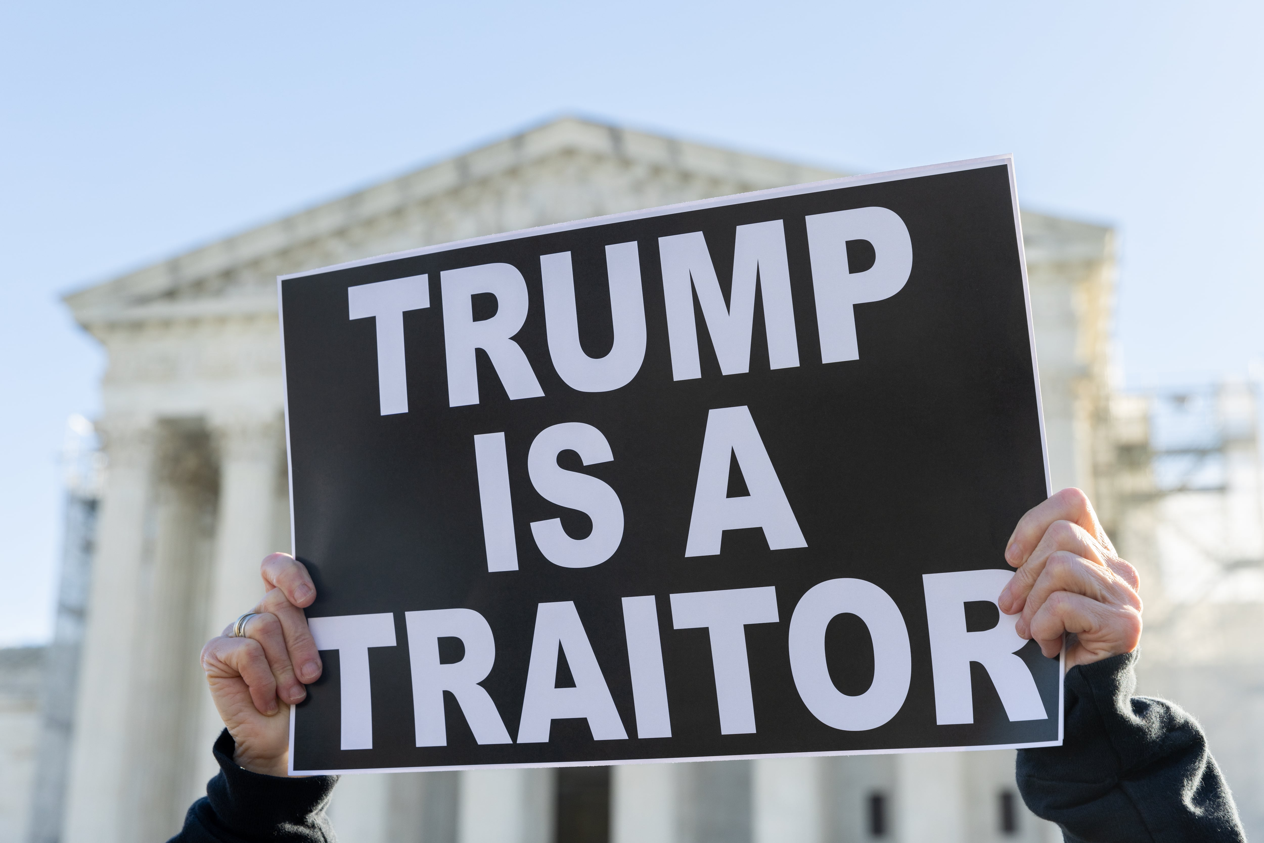 Una manifestante sostiene un cartel en el que acusa a Trump de traidor delante del Tribunal Supremo de EEUU