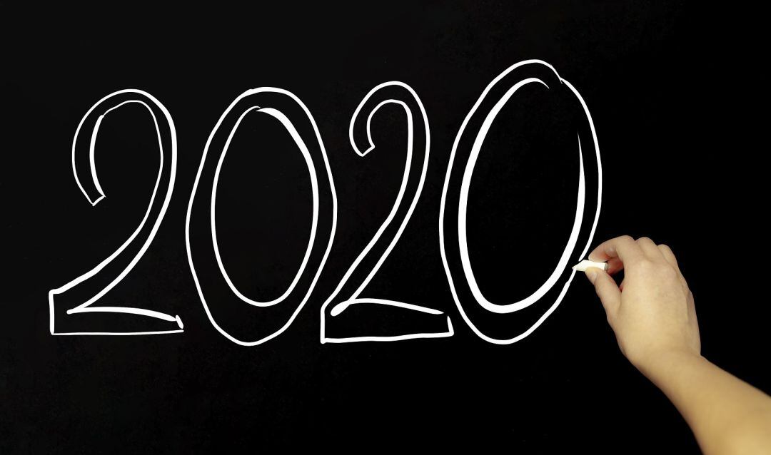 Una mano escribe en una pizarra el año 2020