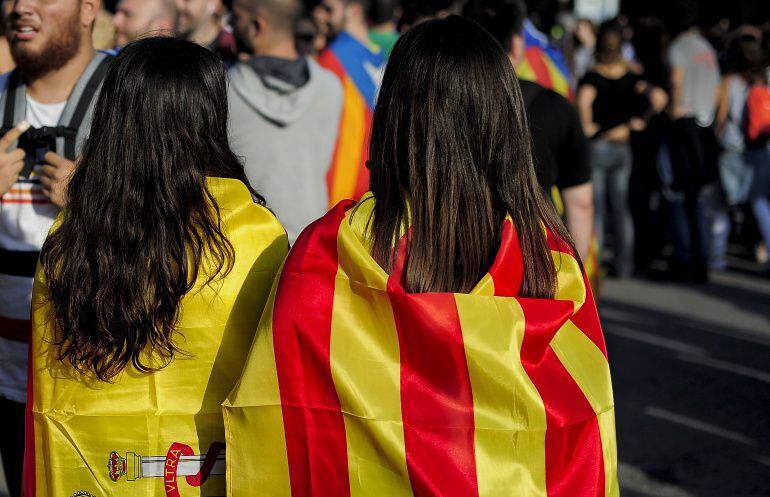 Dos chicas con banderas de España y Cataluña a la espalda.