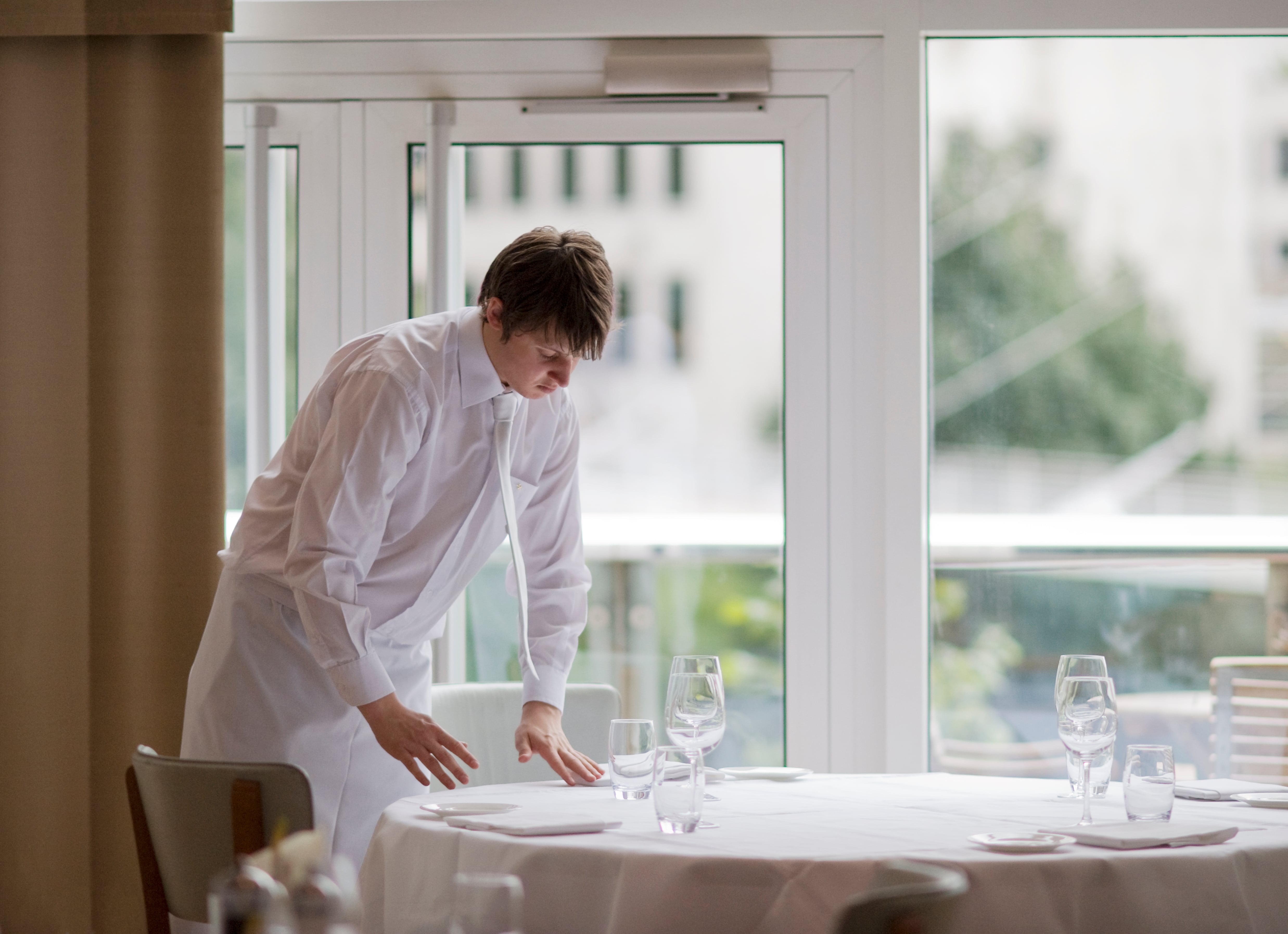 Un camarero prepara una de las mesas de un restaurante