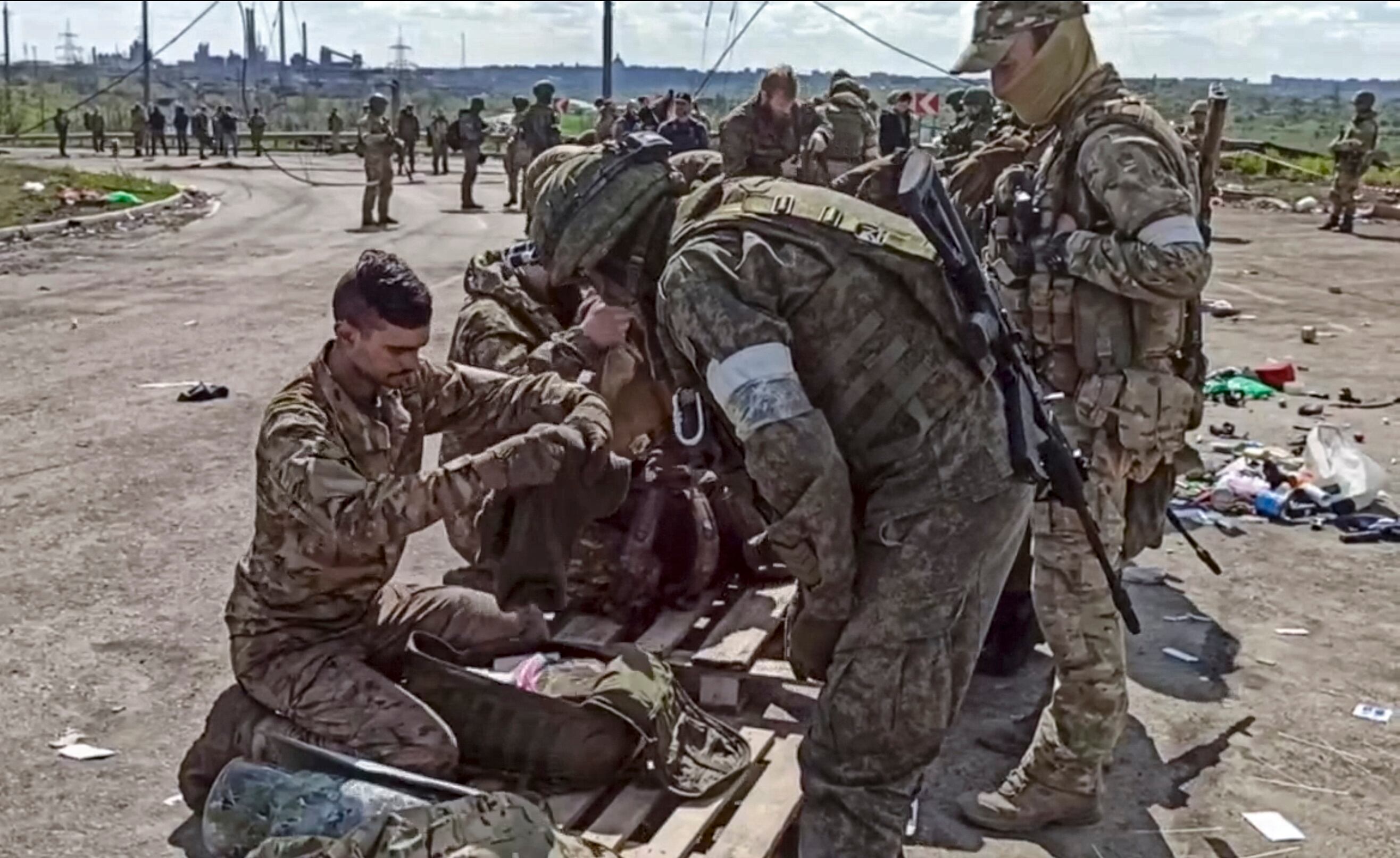 Militares rusos cacheando a militares ucranianos evacuados de la planta siderúrgica Azovstal sitiada en Mariúpol
