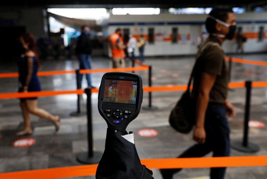 Miden la temperatura a varios pasajeros que pasean por un aeropuerto en México