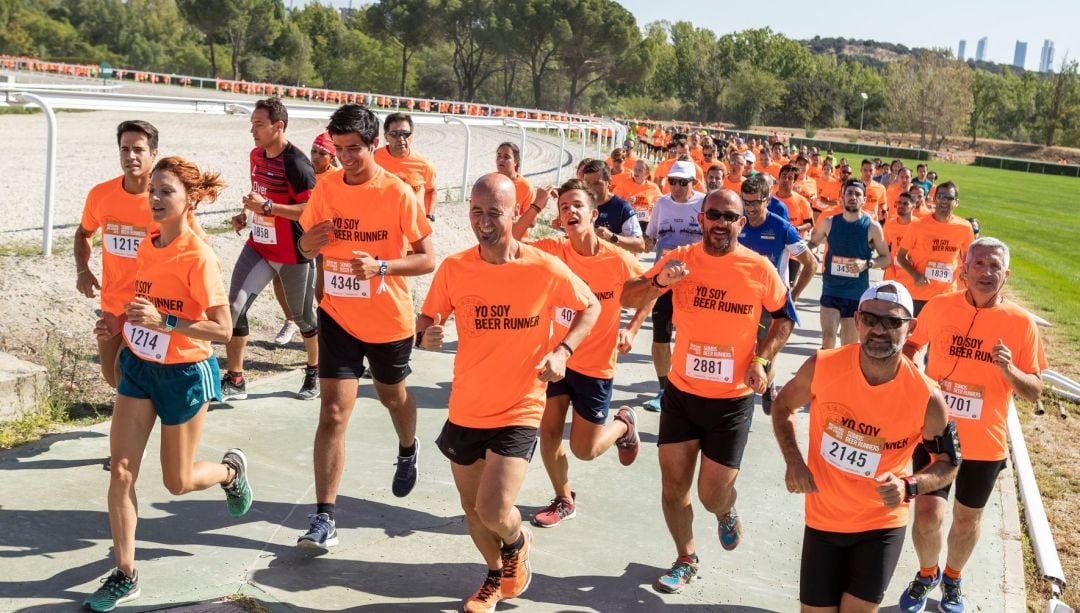 Varios corredores participan en una carrera Beer Runner celebrada en una ciudad.