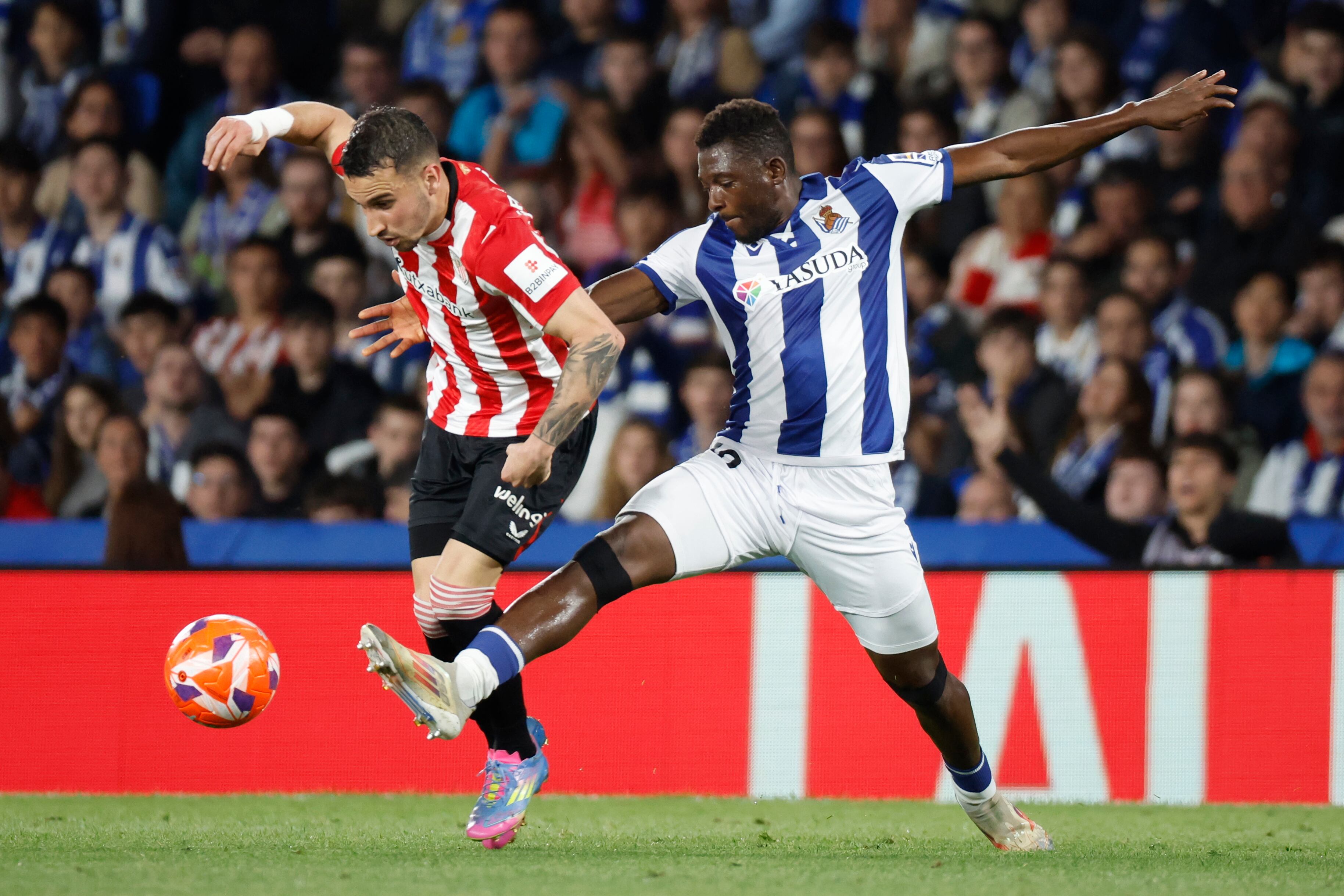 SAN SEBASTIÁN, 04/05/2025.- El defensa maliense de la Real Sociedad Hamari Traoré (d) pelea un balón ante el extremo del Athletic Álex Berenguer, durante el partido de LaLiga EA Sports de fútbol que Real Sociedad y Athletic Club disputan este domingo en el Reale Arena, en San Sebastián. EFE/Juan Herrero
