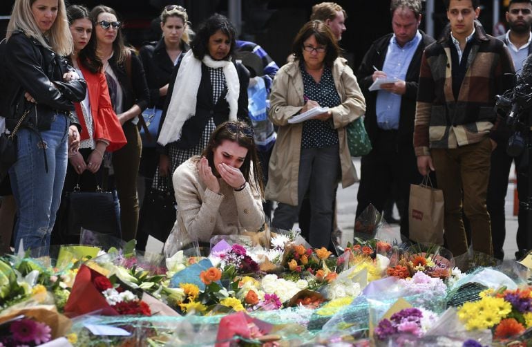 Una mujer llora mientras contempla las flores colocadas como homenaje a las víctimas del atentado terrorista del pasado sábado en Londres