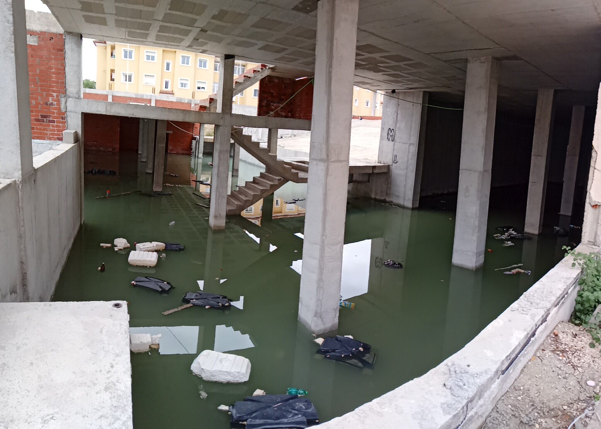 &quot;Piscina&quot; de agua, con basura y otros restos, que se ha formado en las obras de construcción del futuro auditorio municipal.