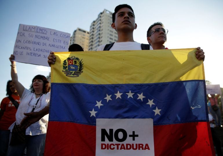  Opositores con banderas de venezuela en las que se puede leer, no mas dictadura. 