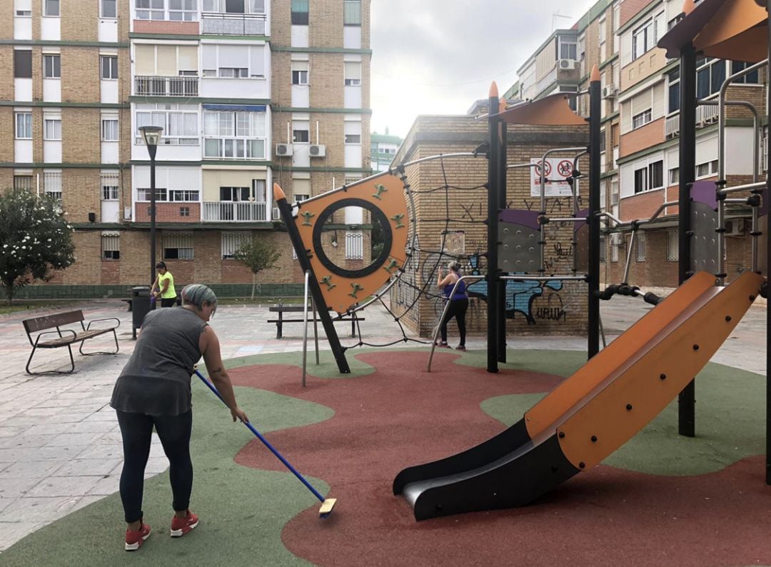 Madres limpiando este jueves el parque infantil público de Puerta Blanca