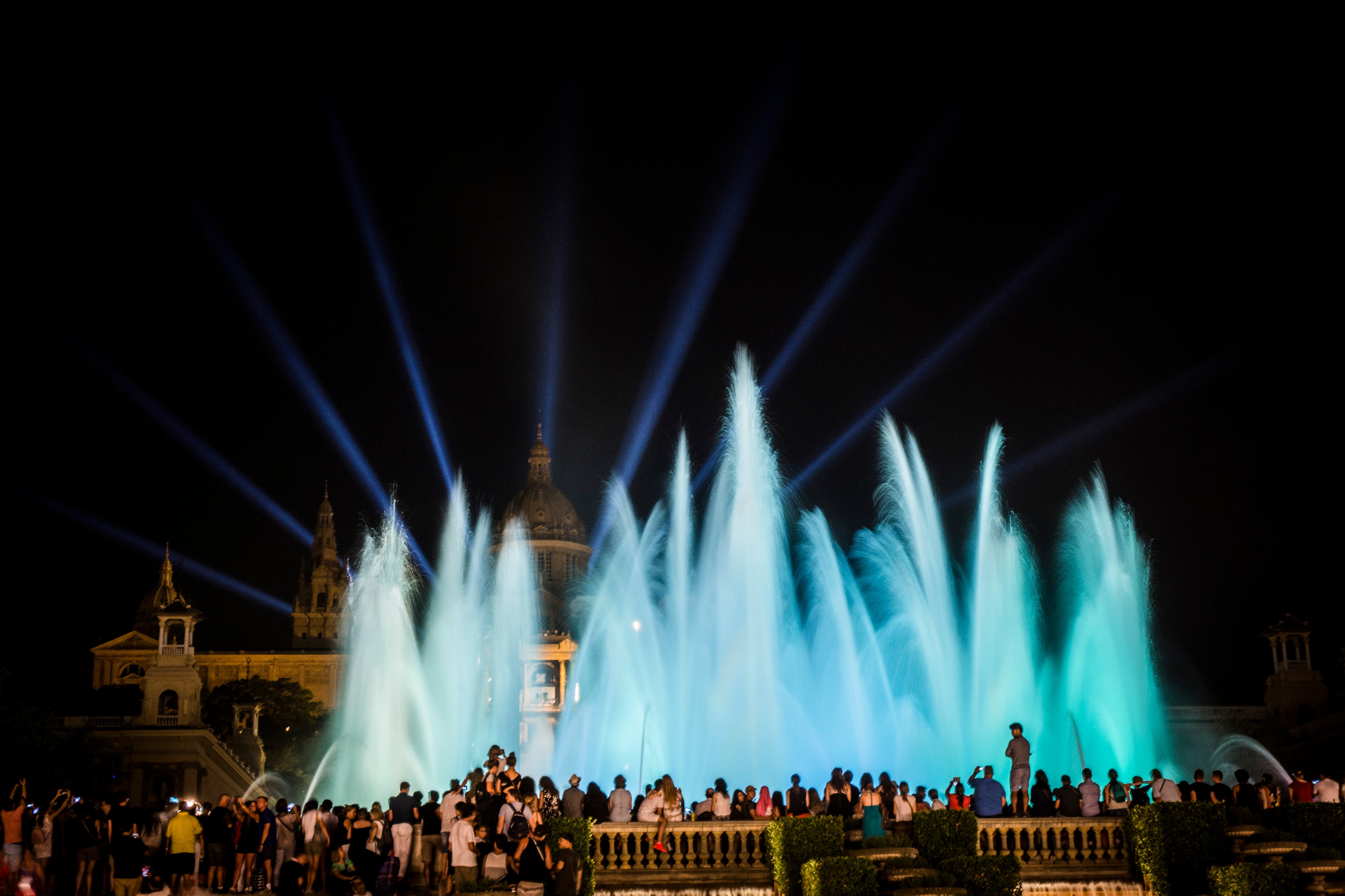 BARCELONA, SPAIN - September 3rd, 2016: Tourists watch the Barcelona Magic Fountain of Montjuïc (Font màgica) and light show, a free tourist attraction. The fountain was originally built in 1929 for the Great Universal Exhibition, and restored in 1992. Located on Avinguda de la Reina Maria Cristina, in the Sants-Montjuïc district of Barcelona, linking Plaça d'Espanya with Museu Nacional d'Art de Catalunya on Montjuïc hill.