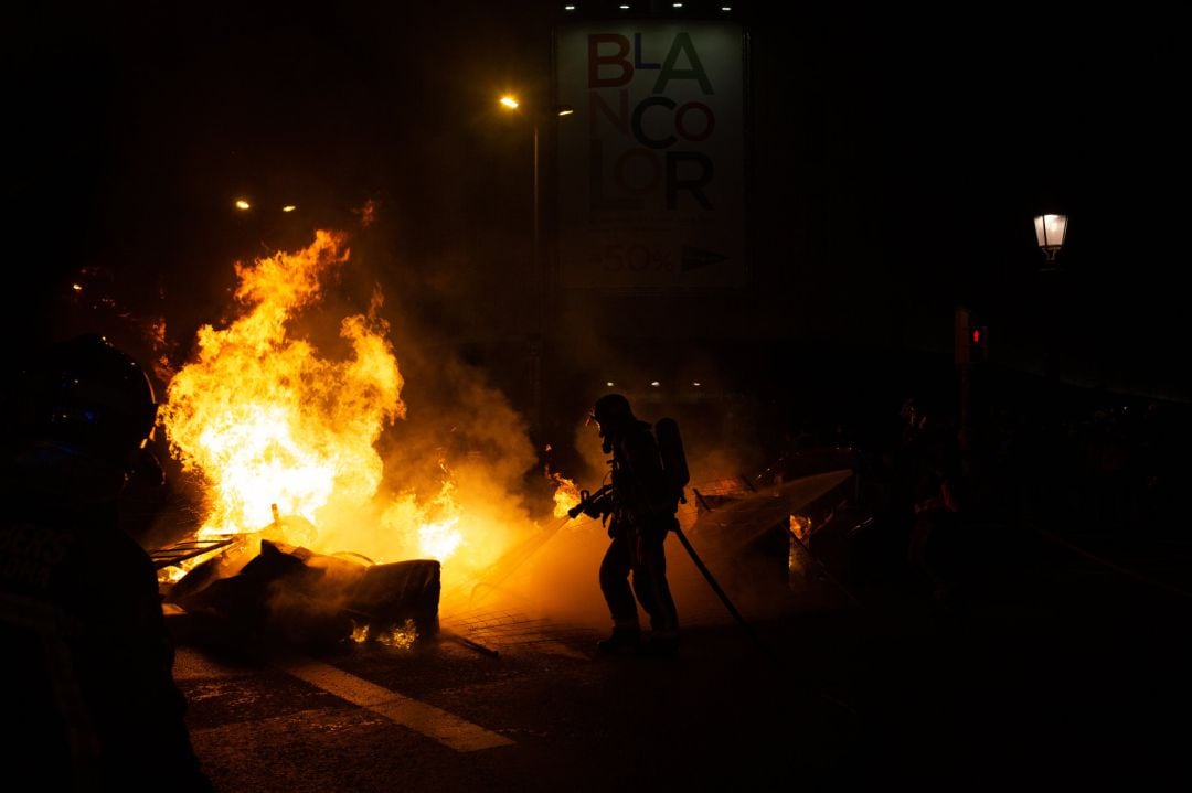 Bomberos apagan un incendio provocado por los manifestantes que apoyan a Pablo Hasel durante los disturbios en Barcelona 