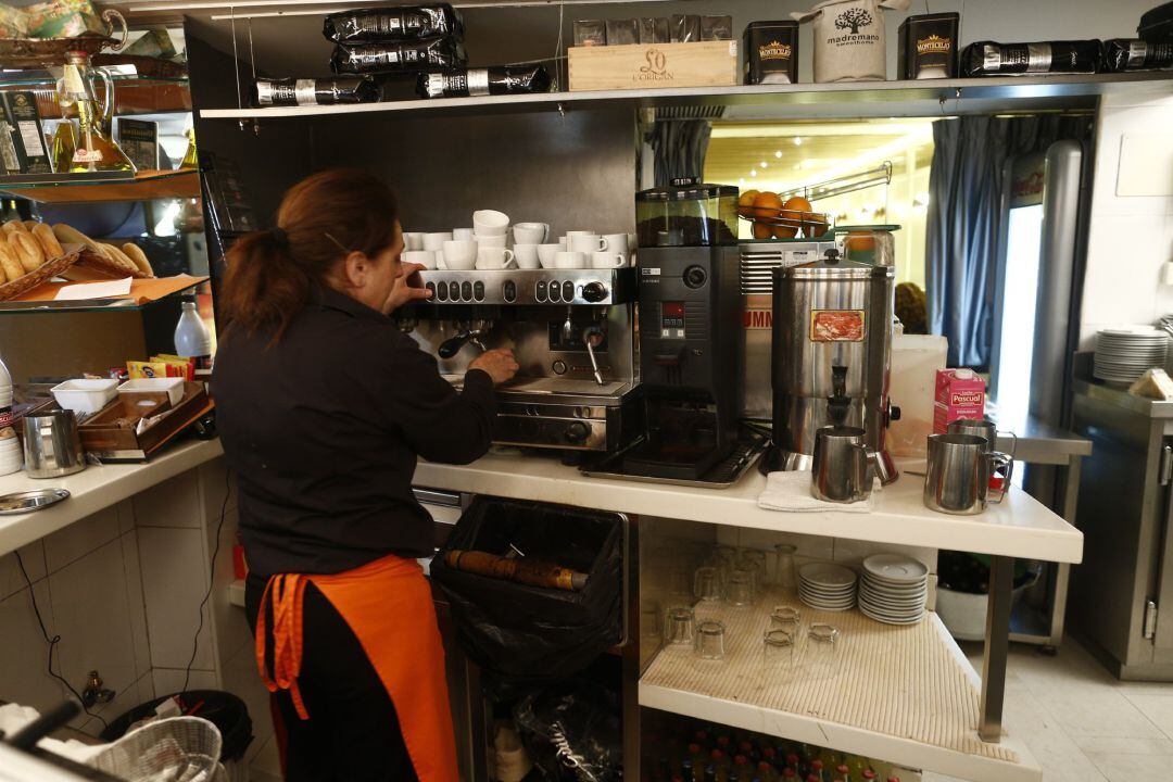 Empleada de hostelería sirviendo un café.