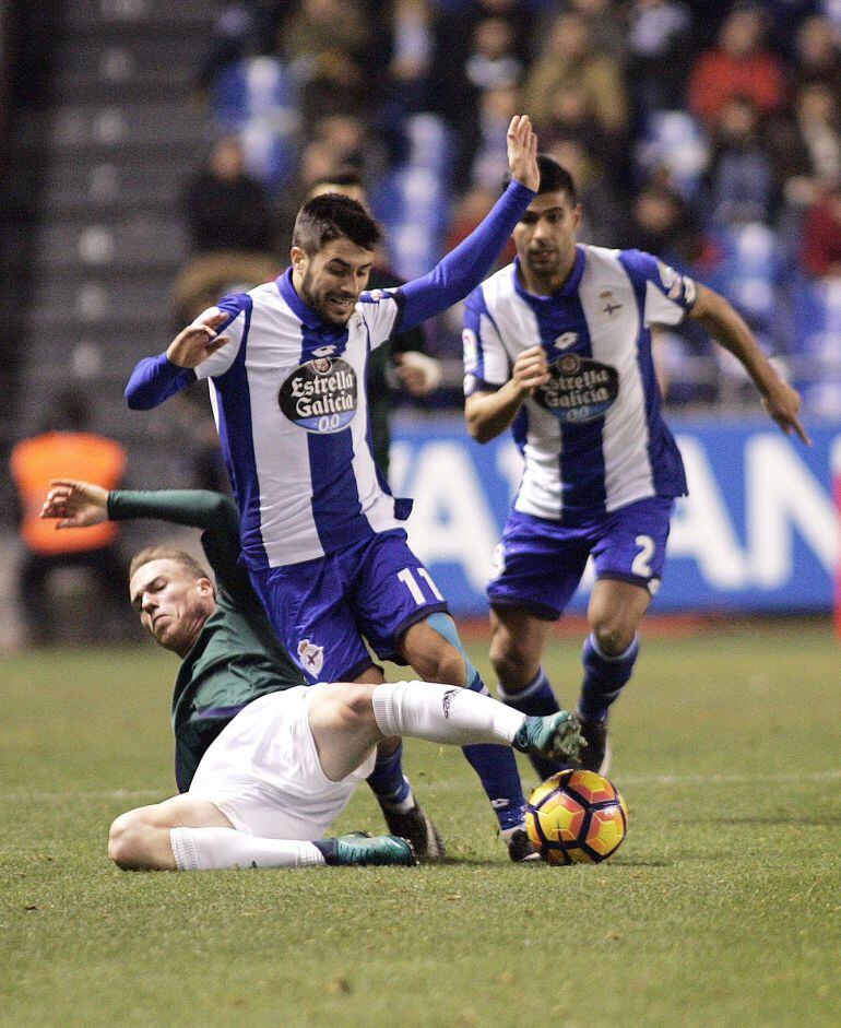 El centrocampista brasileño del Deportivo Guilherme dos Santos (d) disputa un balón con el centrocampista Miguel de las Cuevas (i), del Osasuna, durante el partido de la decimosexta jornada de la Liga de Primera División que se jjugó en el estadio de Riaz