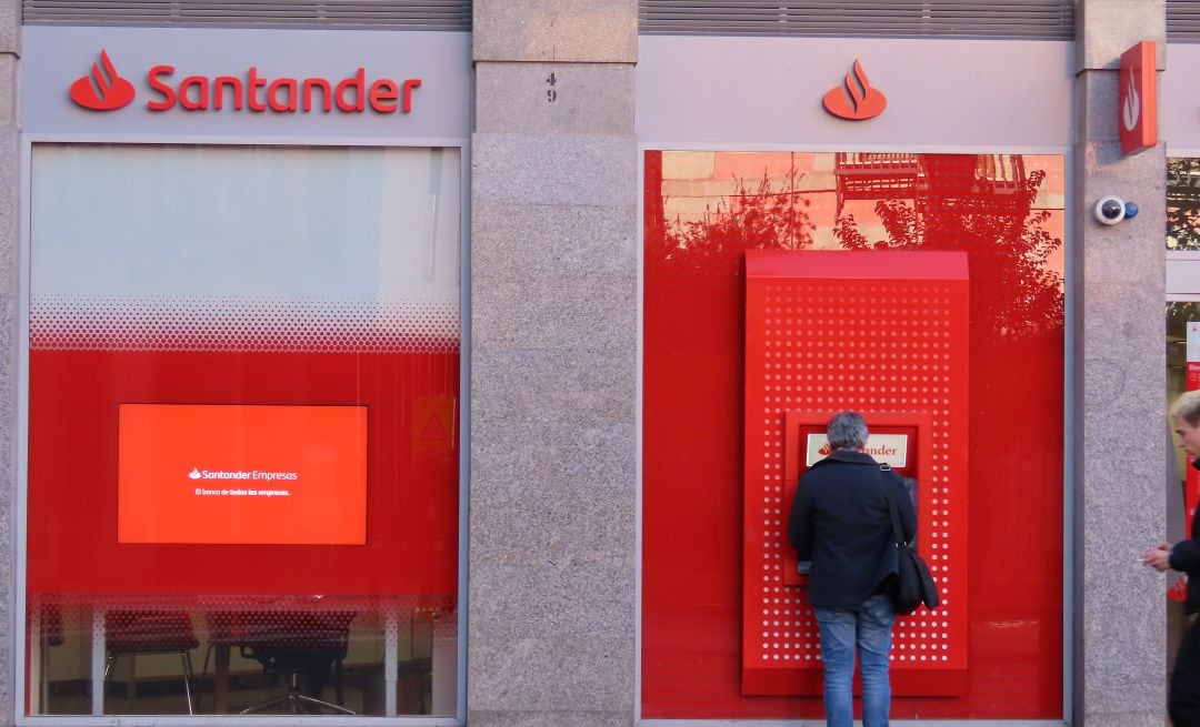 Una persona realiza varias acciones en un cajero del Banco Santander.