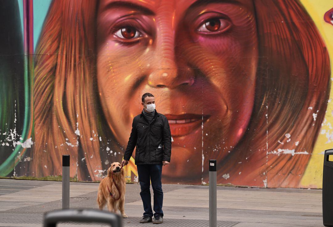 Un hombre pasea con su perro por la Gran Vía de Madrid. 