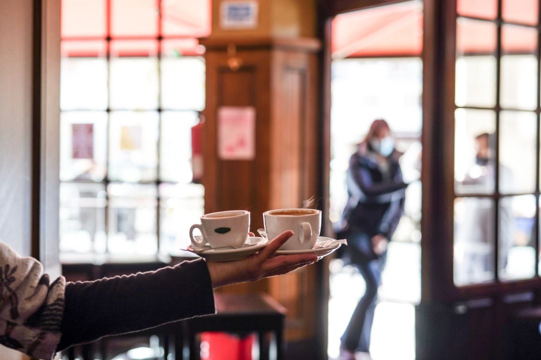 Un camarero sirve varios cafés en una cafetería 