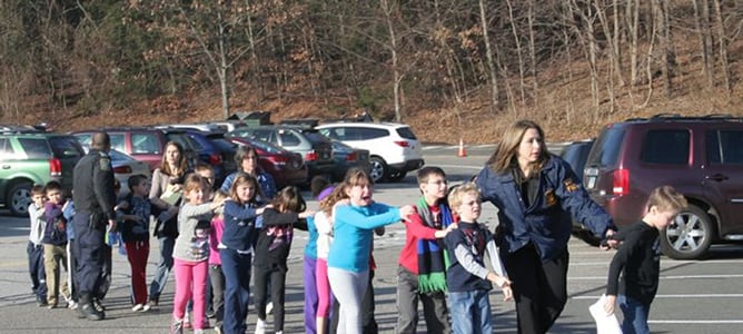 Agentes de seguridad escoltan a alumnos del colegio Sandy Hook (Connecticut) donde se ha perpetrado el tiroteo.