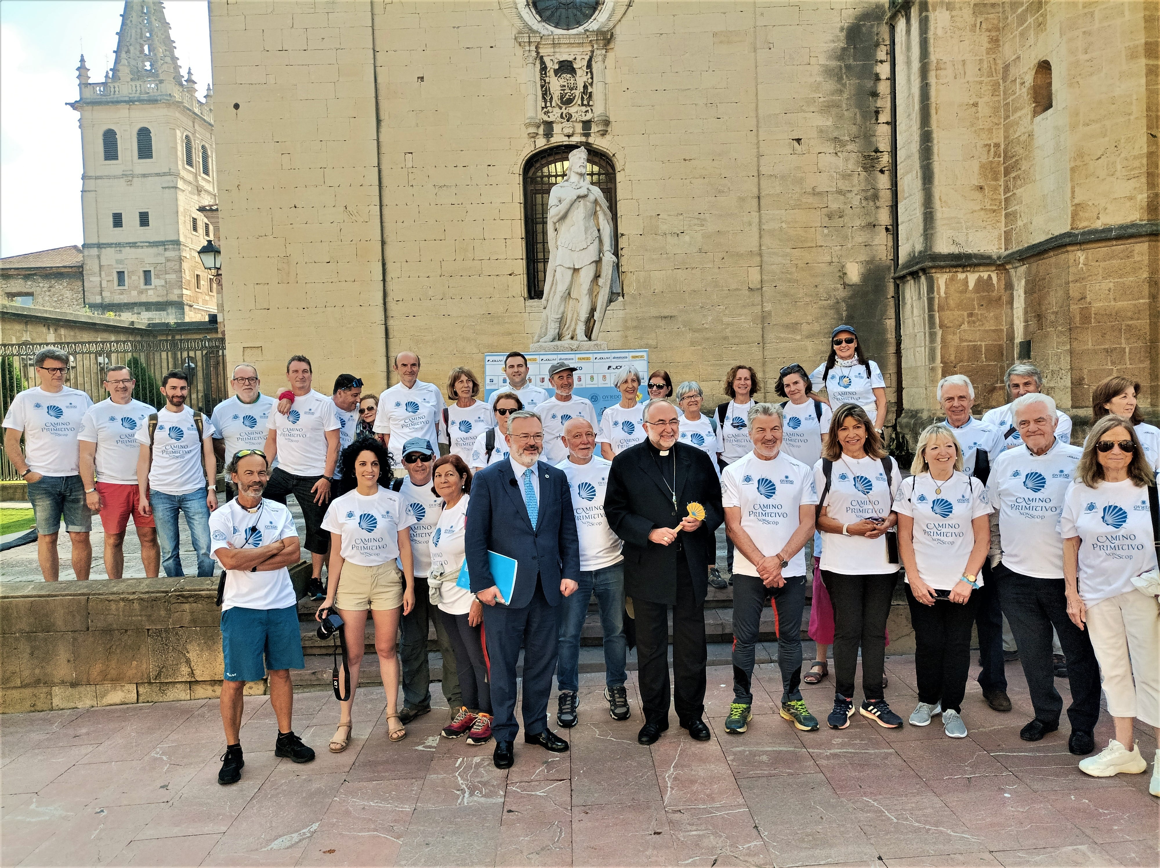 El arzobispo de Oviedo, Jesús Sanz Montes, rodeado de miembros de la Asociación Asturleonesa de Amigos del Camino de Santiago ante la estatua de Alfonso II El Casto