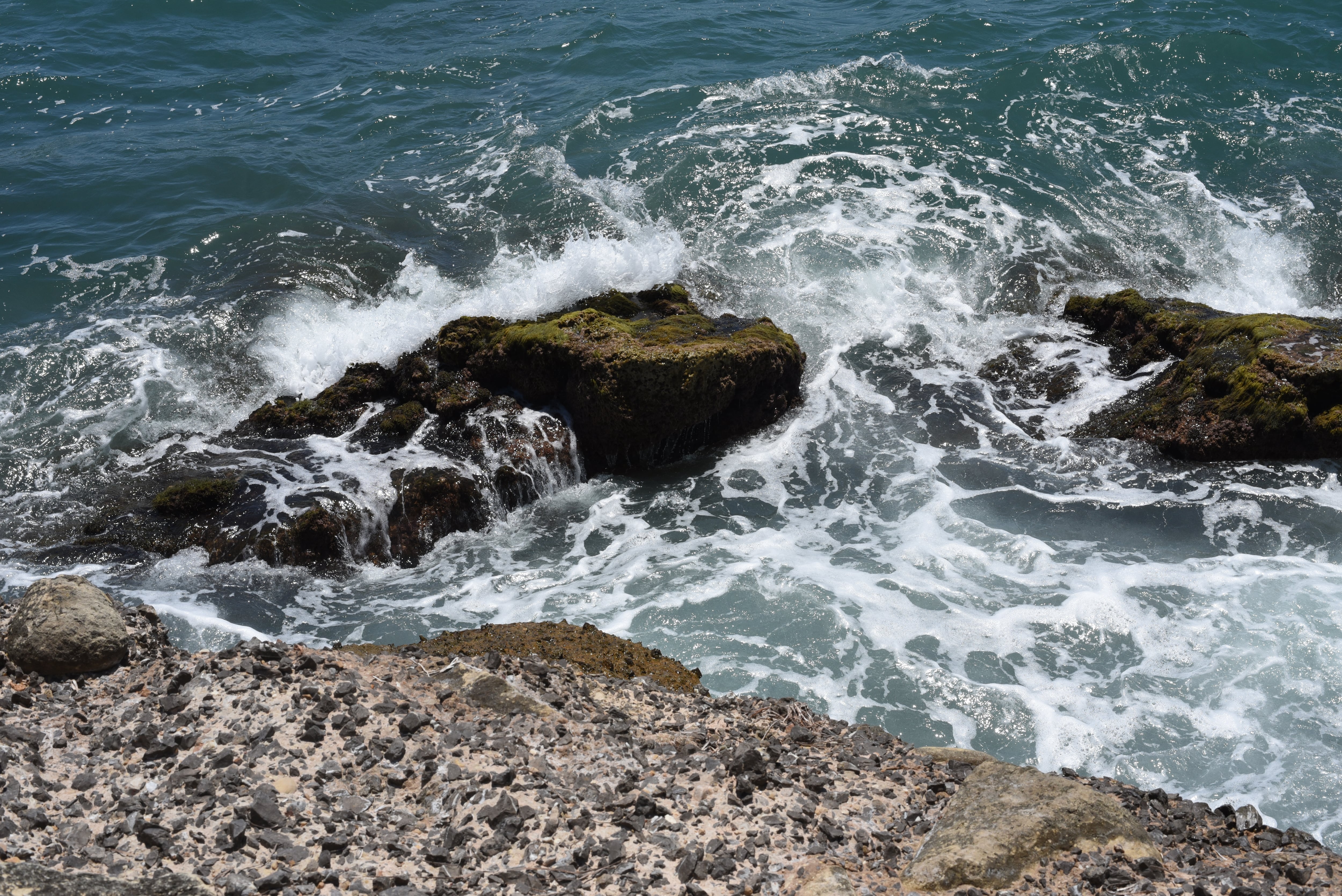 Una ola rompe contra las rocas en una playa de Alicante