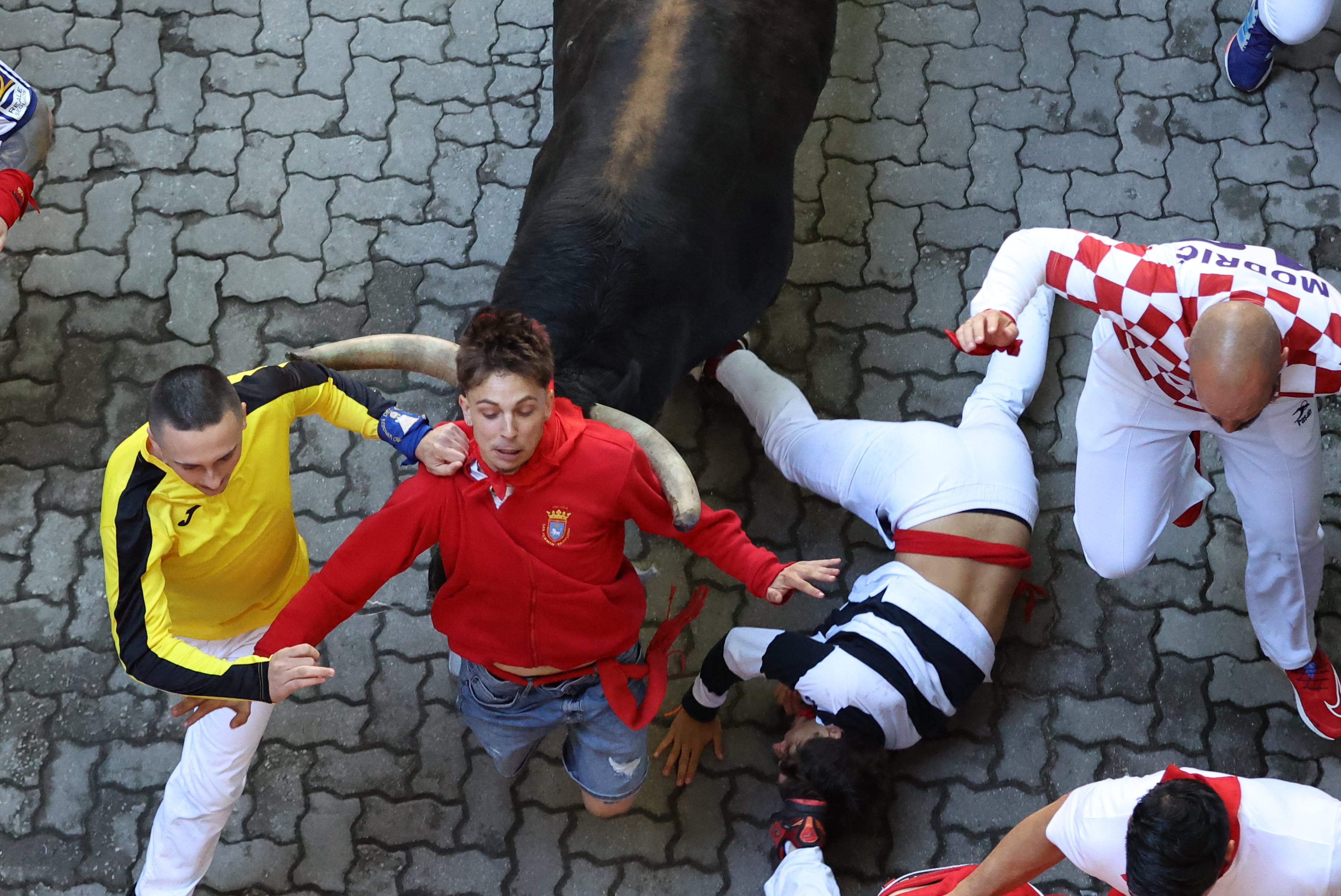 PAMPLONA, 07/07/2024.- Un toro arrolla a un corredor en el tramo final que desemboca en el callejón de la Plaza de Toros de Pamplona en el primer encierro de los Sanfermines este domingo en el Día de San Fermín, copatrón de Pamplona, ciudad que celebra los Sanfermines, Fiesta de Interés Turístico Internacional, hasta el próximo 14 de julio. EFE/ J.P. Urdiroz
