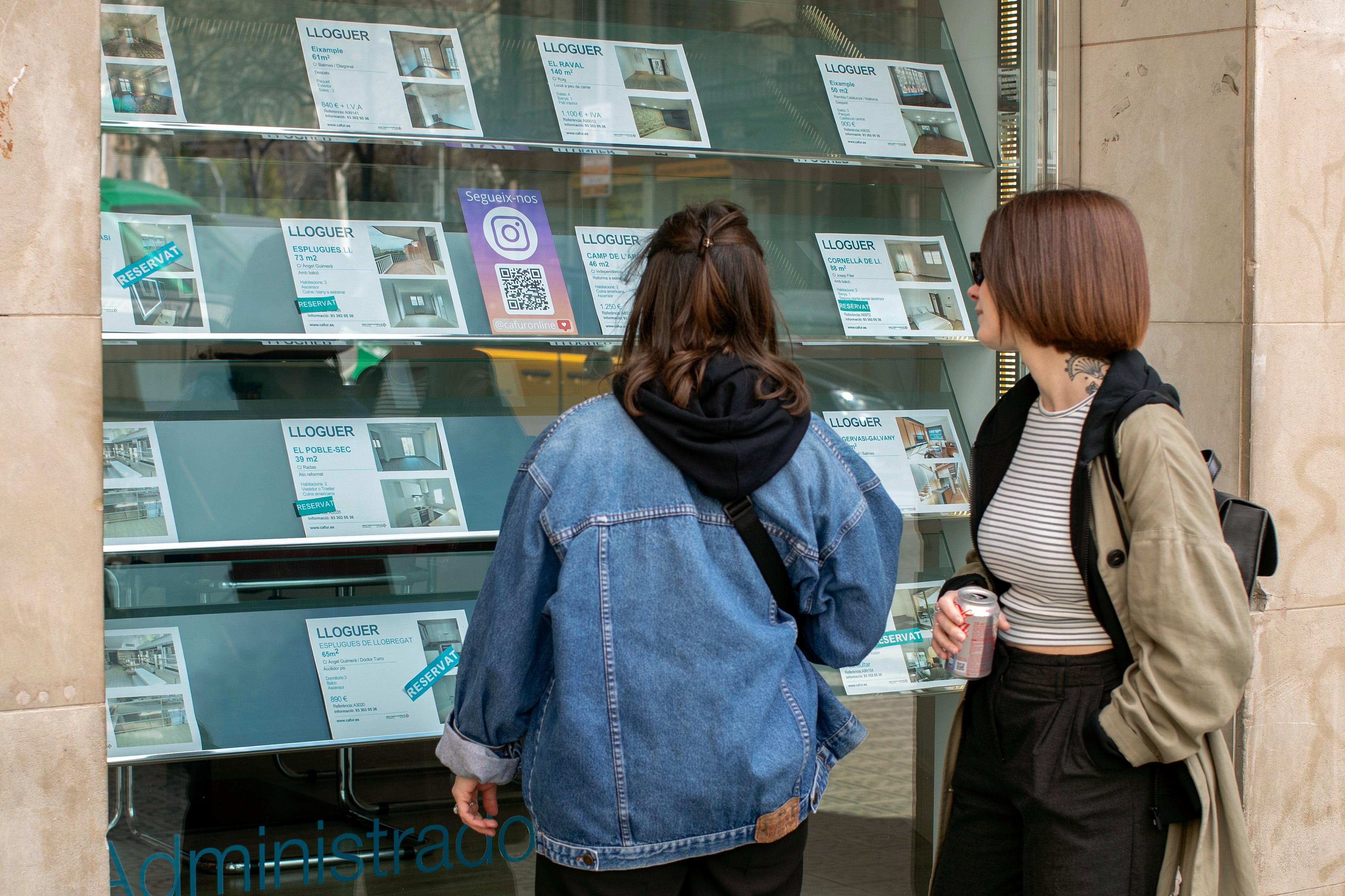 Dos personas observan la oferta de pisos en alquiler de una oficina inmobiliaria de Barcelona