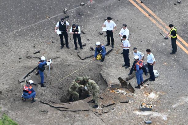 Autoridades japonesas examinan los agujeros provocados por la explosión en el aeropuerto de Miyazaki.