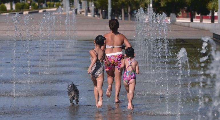 Una mujer y dos niñas se refrescan en una de las fuentes de Córdoba.