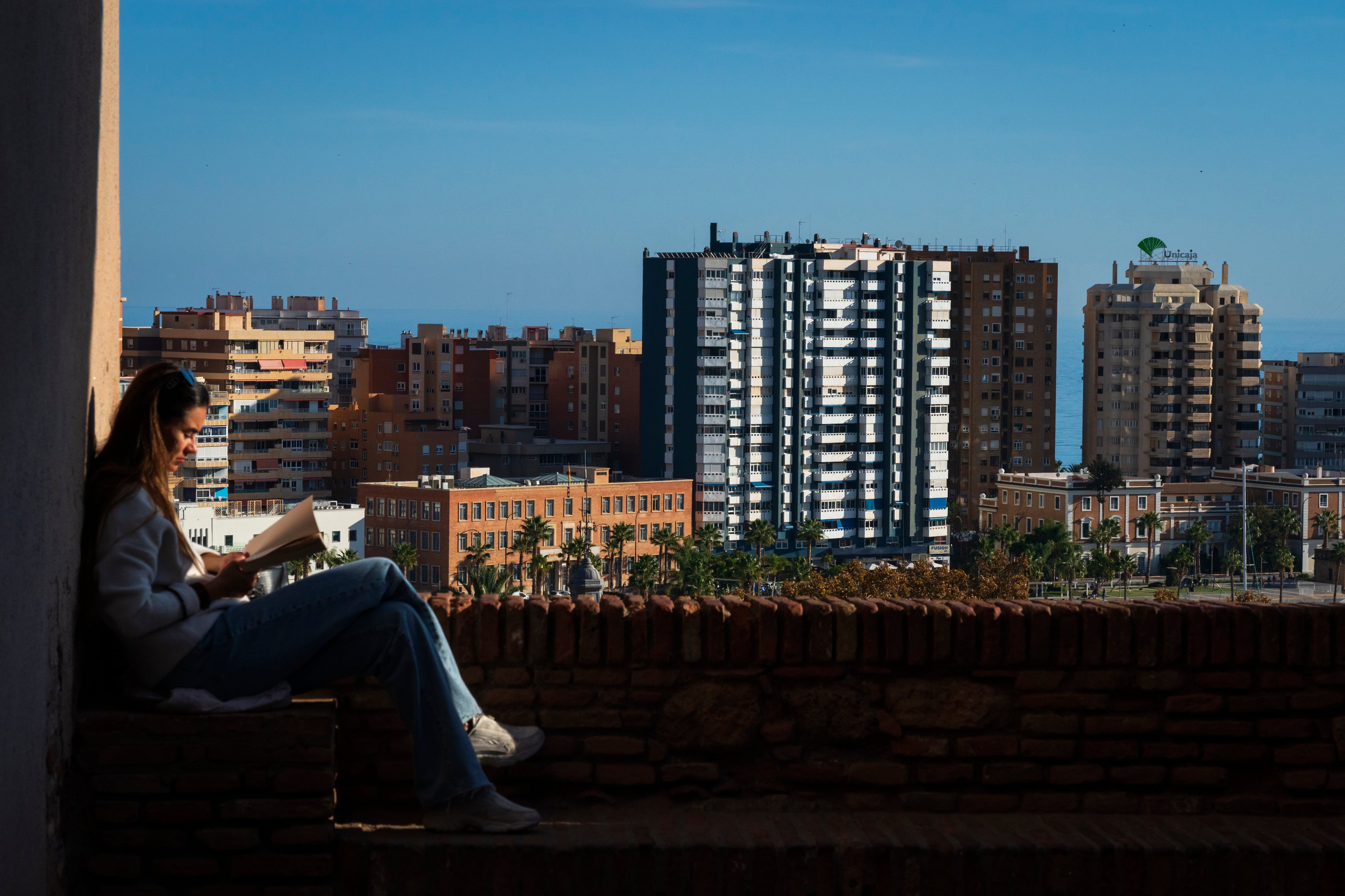 Una mujer lee un libro en Málaga.