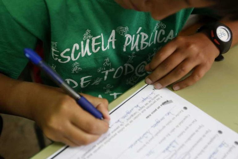 Un alumno del Colegio Joaquín Costa de Madrid rellena una ficha con la camiseta a favor de la escuela pública 