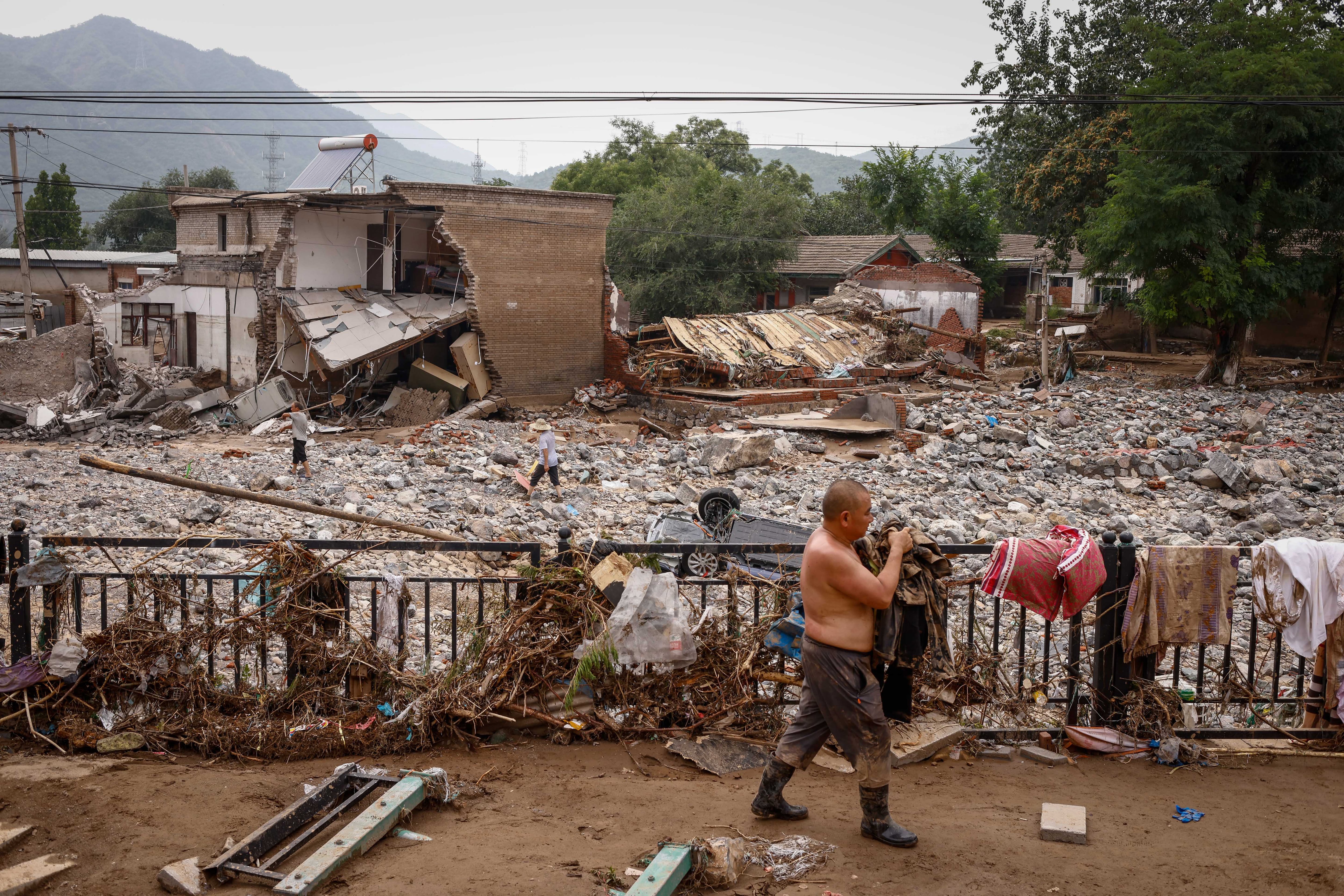 Un hombre recoge sus pertenencias después del paso de los tifones por las cercanías de Pekín