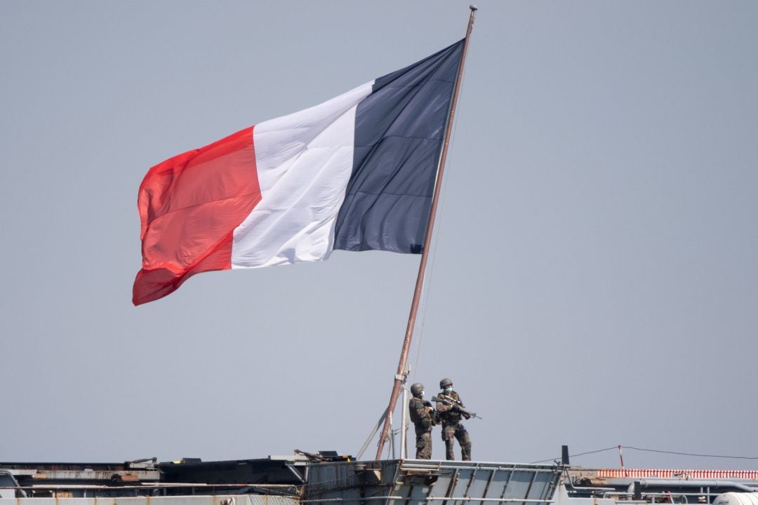 Militares con mascarilla junto a una bandera de Francia