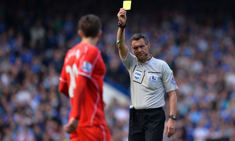 Imagen de un colegiado mostrando una tarjeta amarilla en un partido de la Premier League.