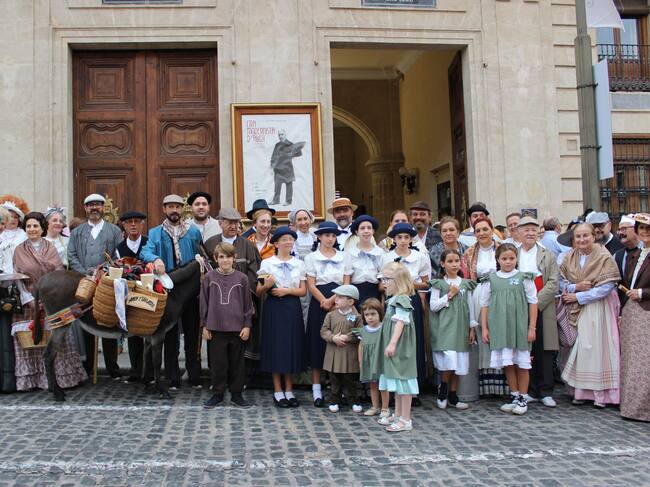 Los componentes del Grup de Danses Carrascal ante el cartel de la Feria Modernista
