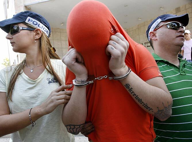 Uno de los arrestados se cubre la cara.