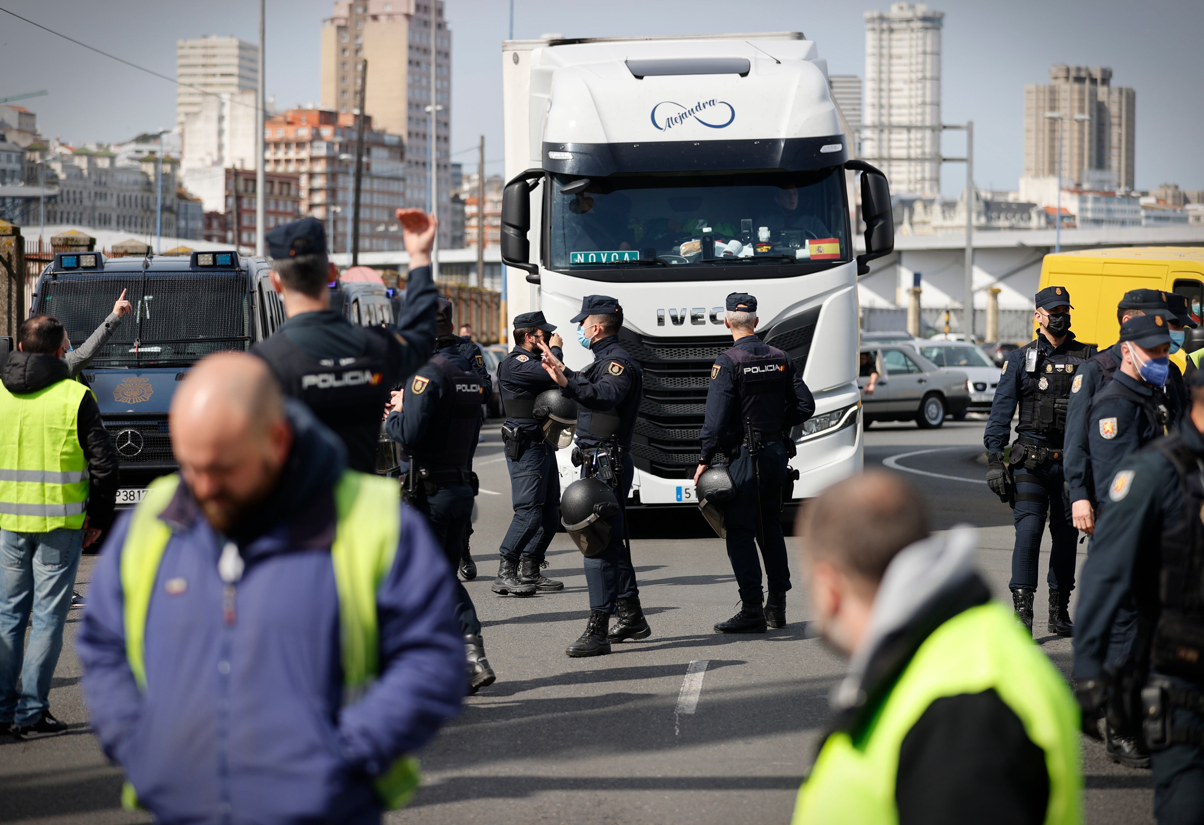 GRAF8666. A CORUÑA, 14/03/2022.- Agentes del Cuerpo Nacional de Policía escoltaban este lunes a uno de los camiones que ha salido del puerto de A Coruña, donde un grupo de alrededor de 50 personas ha montado un piquete informativo con motivo de la huelga en el sector del transporte que se desarrolla desde la pasada medianoche. EFE/ Cabalar
